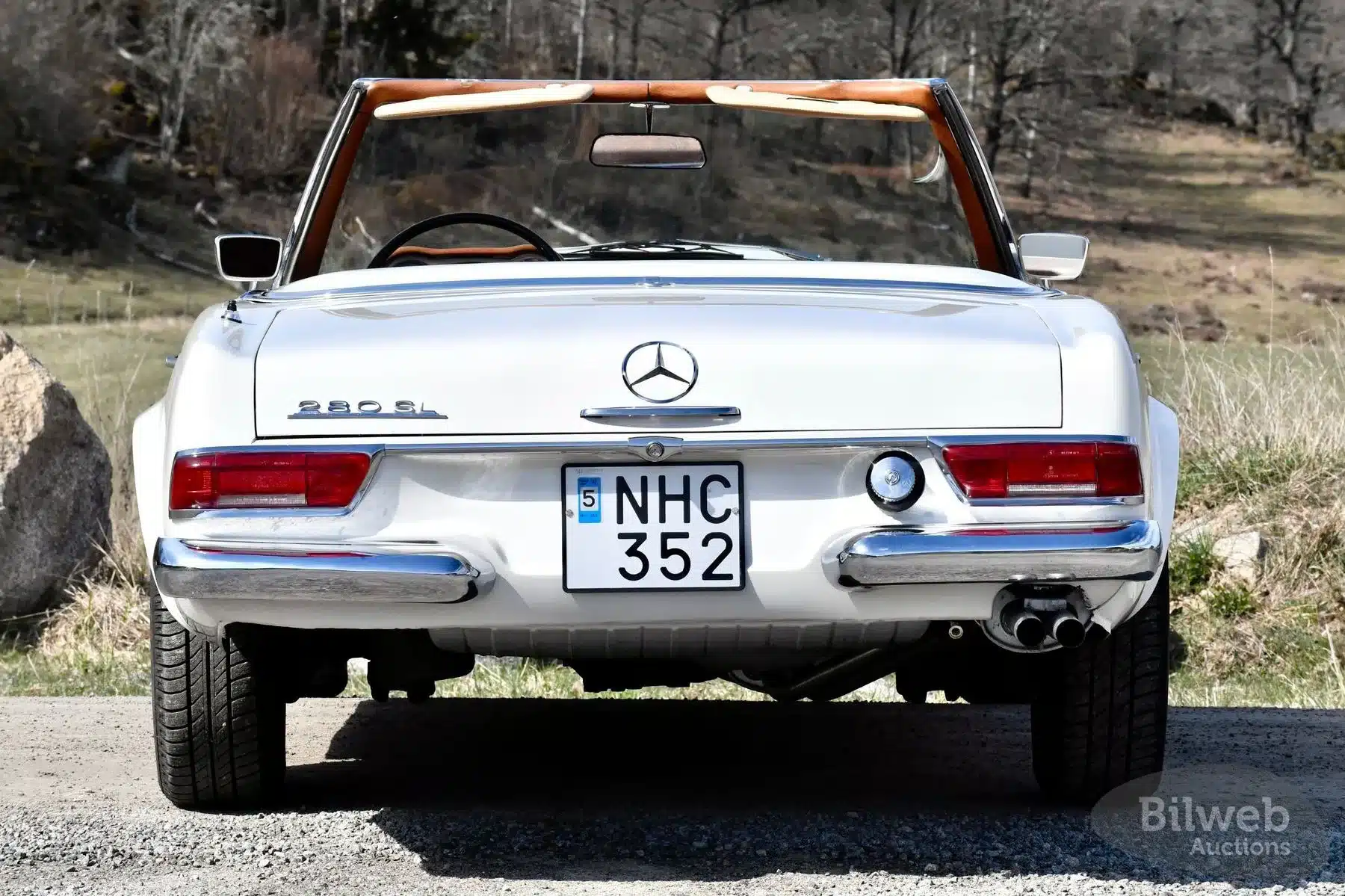 Heckansicht eines weißen Mercedes-Benz 280 SL Pagode Cabriolets mit schwedischem Kennzeichen, offenem Verdeck und natürlicher Umgebung