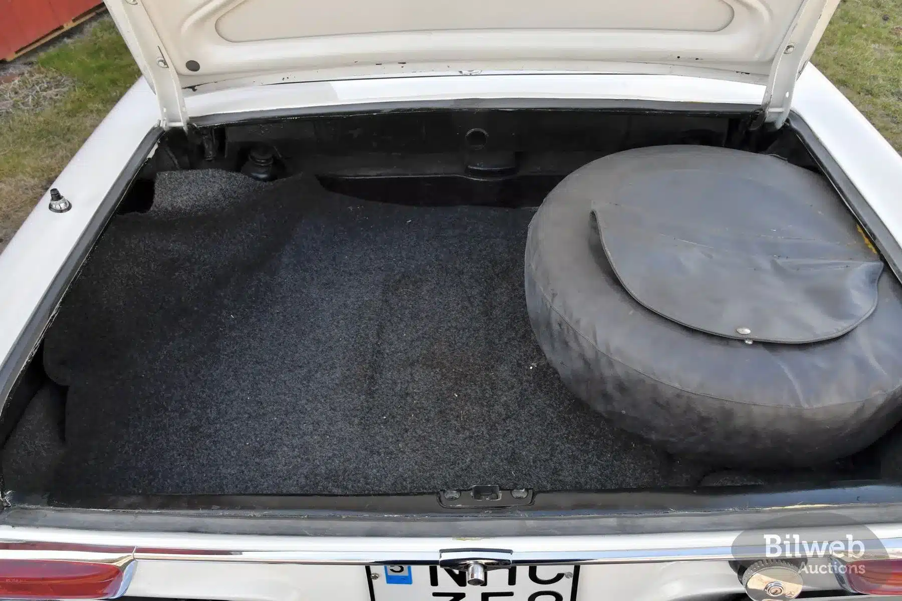 Kofferraum eines weißen Mercedes-Benz 280 SL Pagode mit Reserverad und Auslegeware, geöffnet
