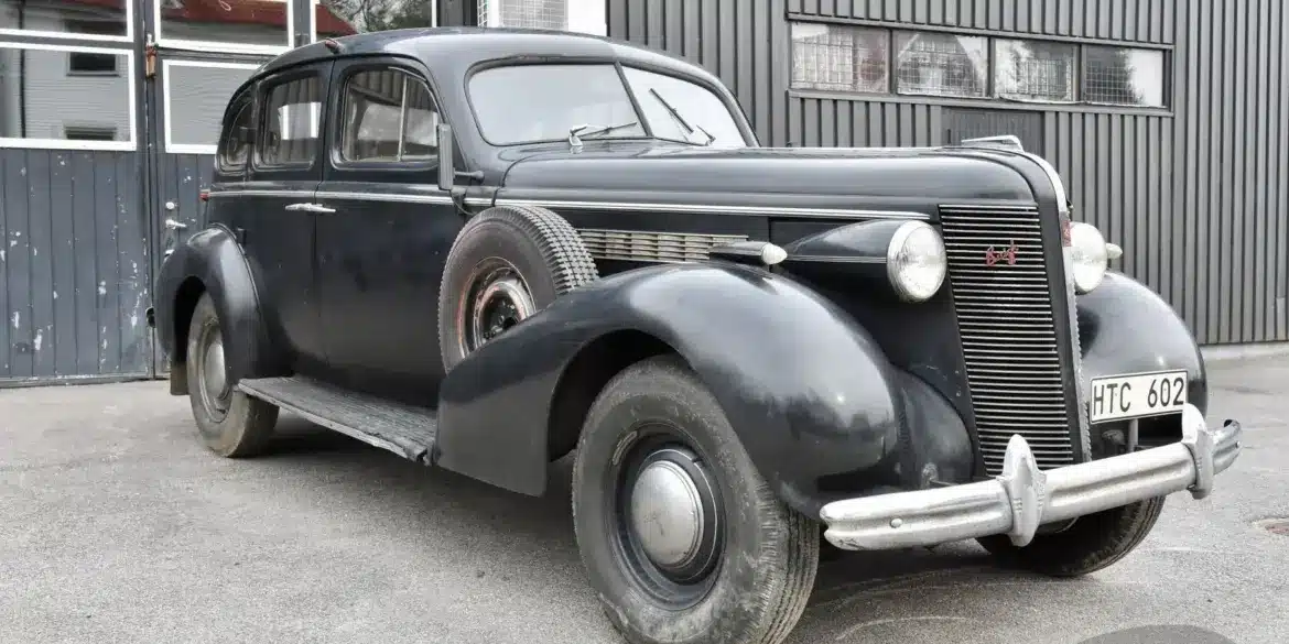 Schwarzer Buick Special Saloon Straight 8 von 1937 mit sichtbarer Patina und stilprägenden Details vor grauer Halle