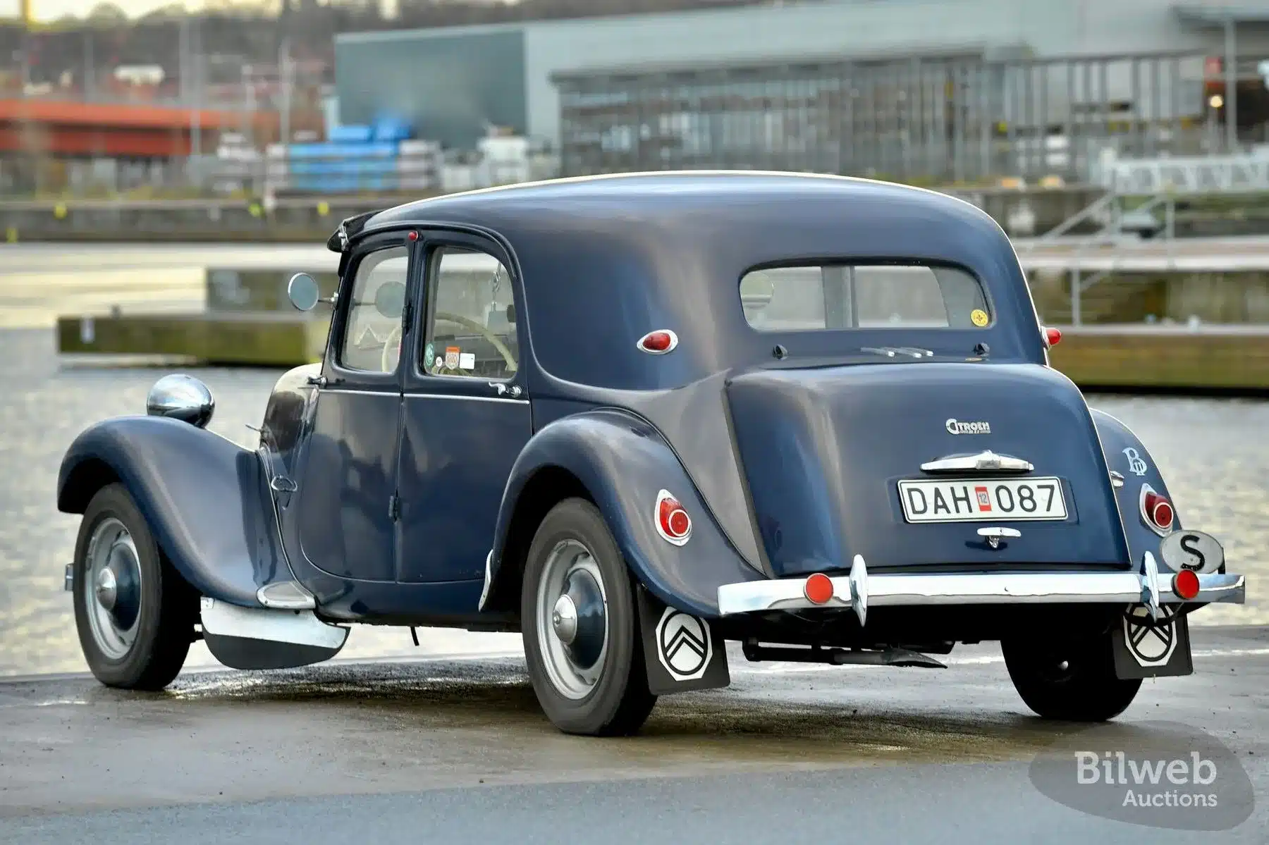 Dunkelblauer Citroën B11 Traction Avant von 1956, von hinten fotografiert, geparkt am Wasser.