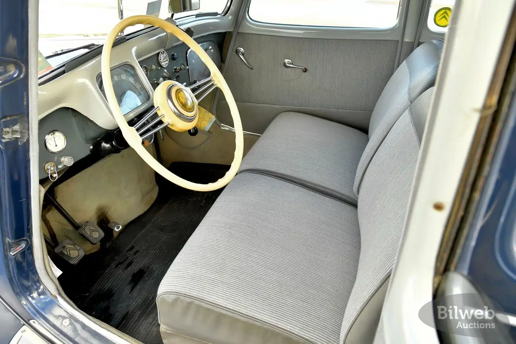 Sicht auf das Armaturenbrett und die Vordersitze eines Citroën B11 Traction Avant von 1956 mit hellgrauen Polstern und Lenkrad.