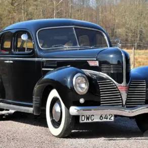 Schwarzer Dodge Senior Touring Sedan von 1939 mit weißwandbereifung, aufgenommen im Freien vor natürlicher Kulisse.