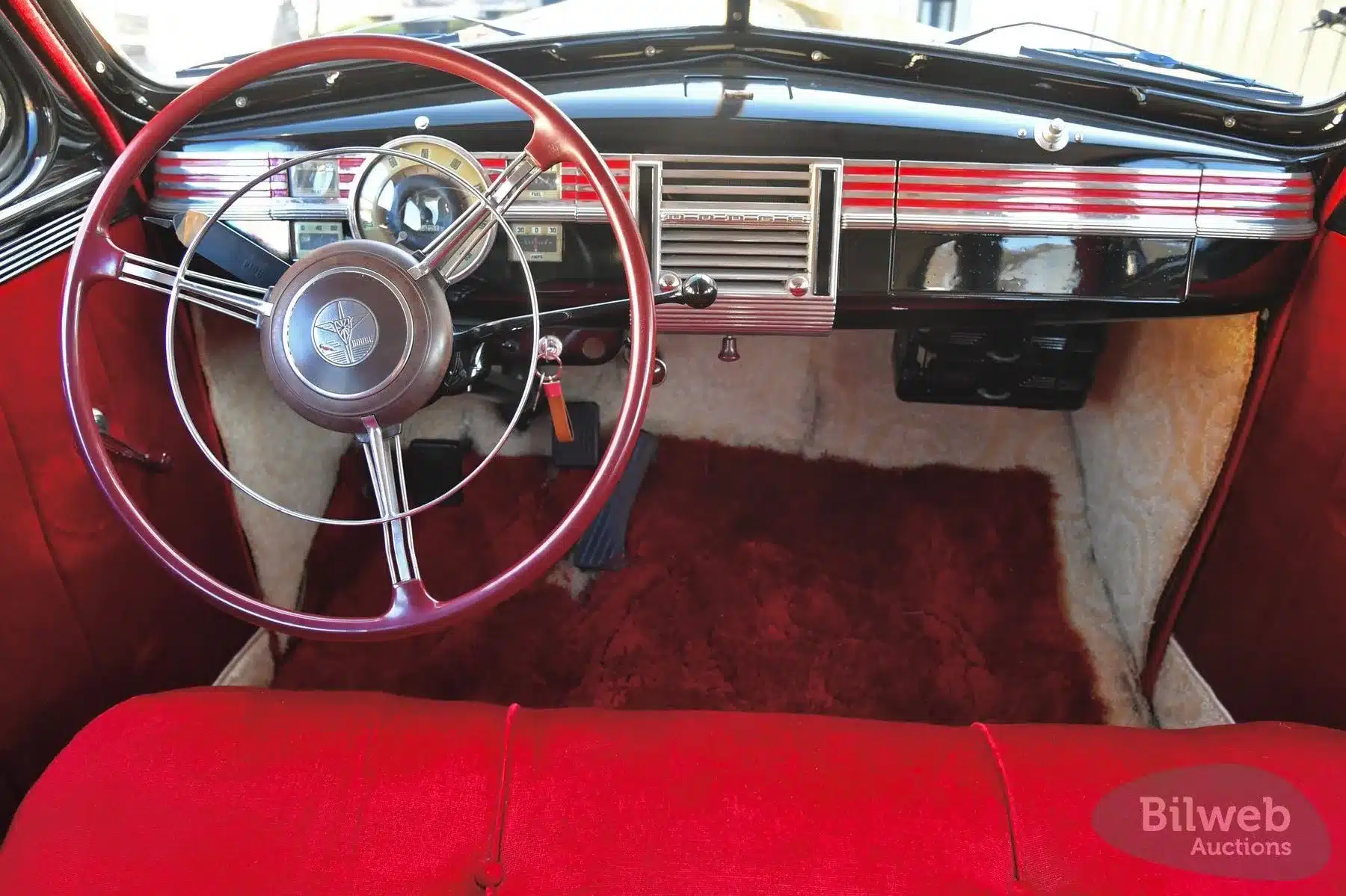 Innenraum eines Dodge Senior Touring Sedan von 1939 mit originalem Armaturenbrett und rotem Lenkrad.