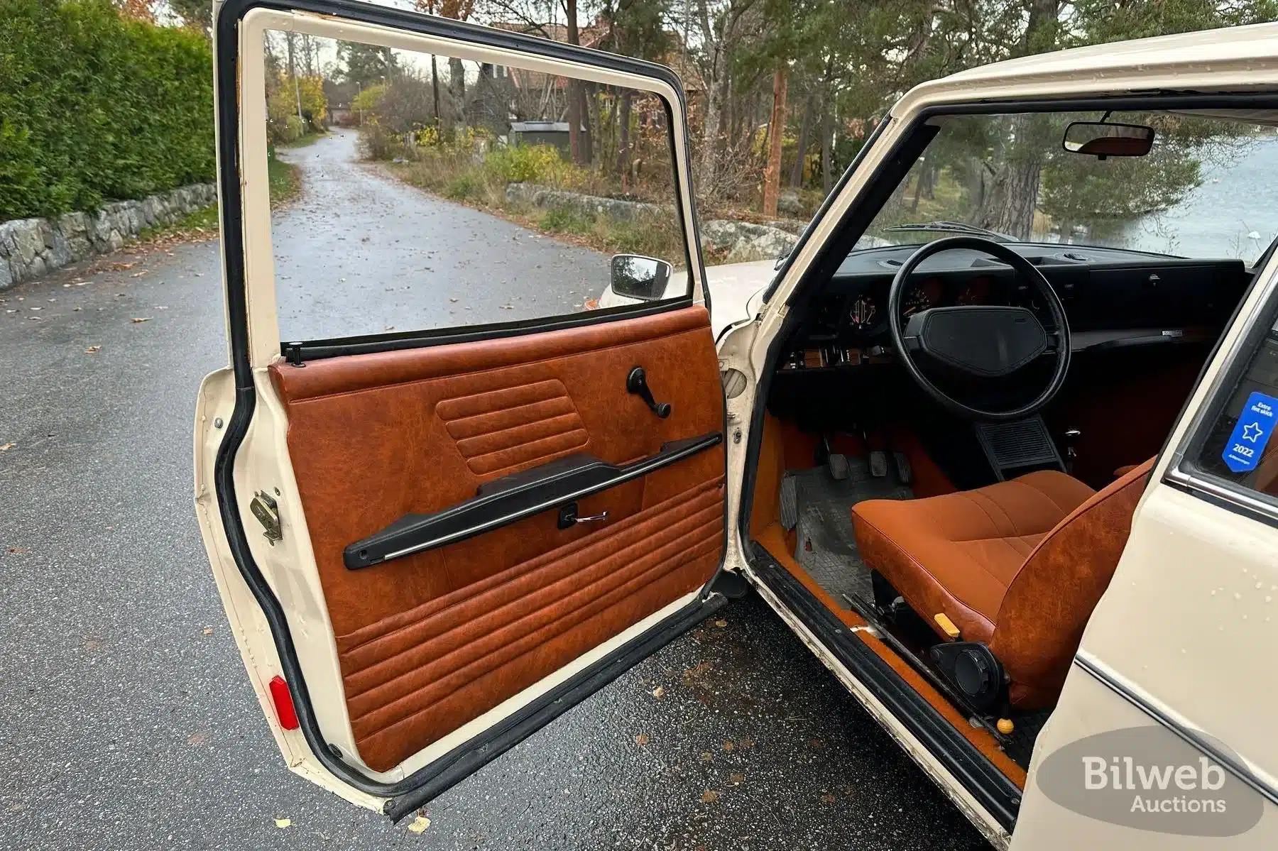 Geöffnete Fahrertür und Innenraum eines Saab 99 GL Baujahr 1976 mit brauner Türverkleidung und orangem Sitz