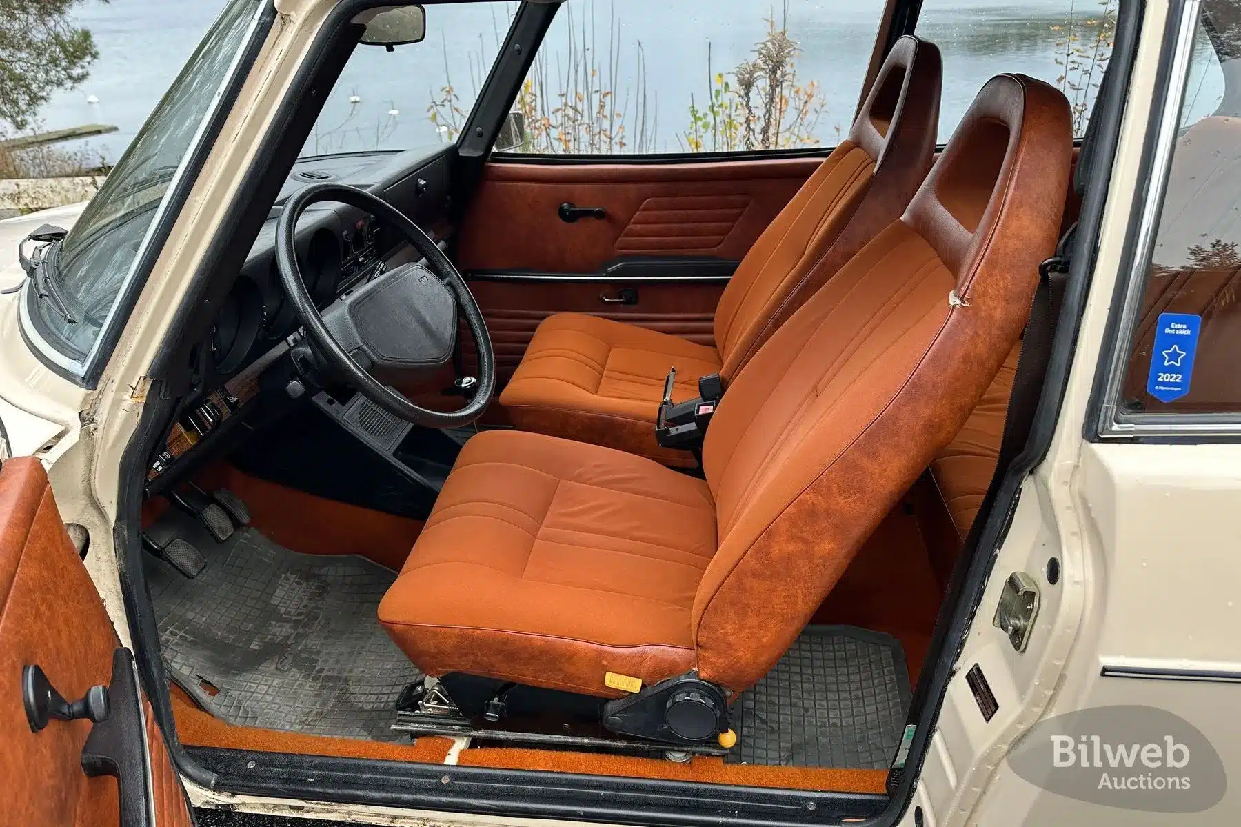 Original-Innenraum eines Saab 99 GL von 1976 mit roten Stoff- und Kunstledersitzen, Lenkrad und Armaturenbrett.