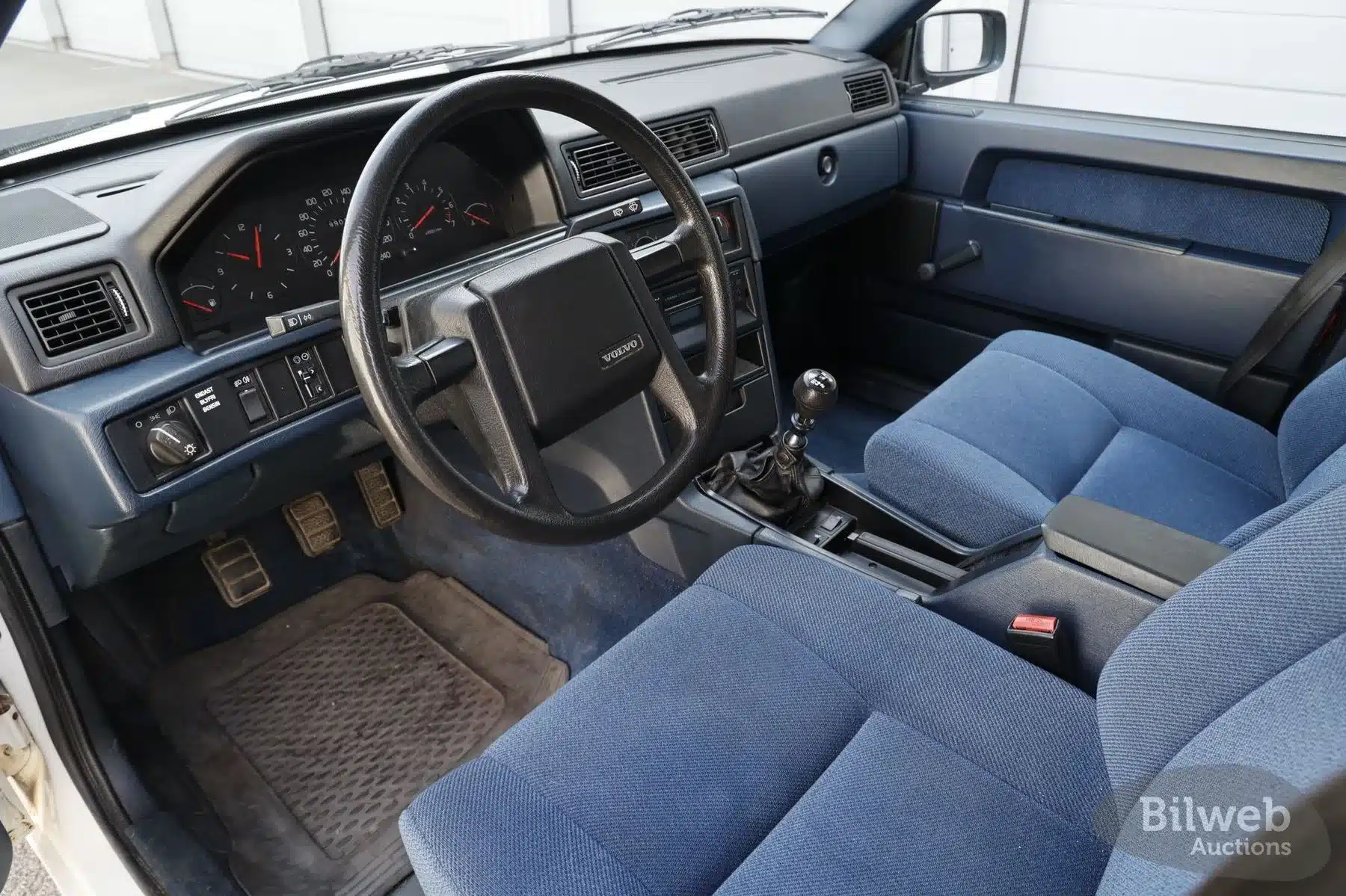 Innenraumansicht eines Volvo 940 von 1990 mit blauer Stoffausstattung und Schaltgetriebe