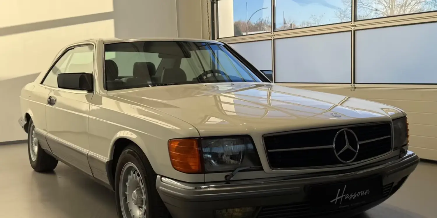 Frontansicht eines Mercedes-Benz 500 SEC Coupés in cremeweiß, stehend in einer hellen Garage