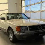 Frontansicht eines Mercedes-Benz 500 SEC Coupés in cremeweiß, stehend in einer hellen Garage