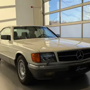 Frontansicht eines Mercedes-Benz 500 SEC Coupés in cremeweiß, stehend in einer hellen Garage