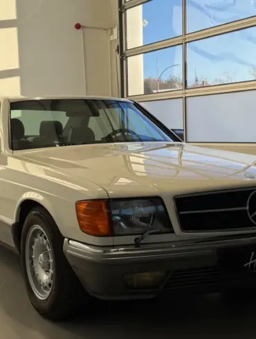 Frontansicht eines Mercedes-Benz 500 SEC Coupés in cremeweiß, stehend in einer hellen Garage