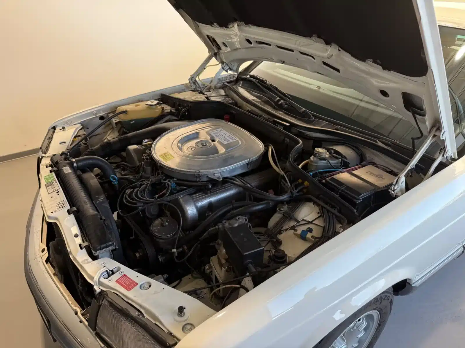 Offener Motorraum eines Mercedes-Benz 500 SEC mit sichtbarem V8-Motor.