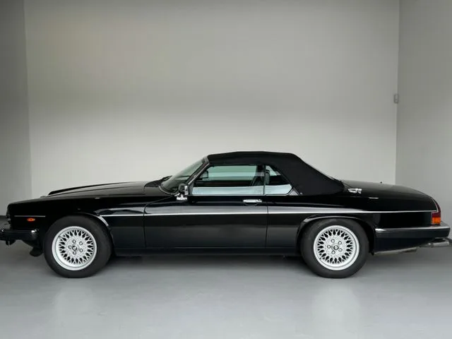 Schwarzer Jaguar XJS V12 2+2 Cabriolet mit geschlossenem Verdeck und exklusiven Arden-Alufelgen in Seitenansicht im Fotostudio.