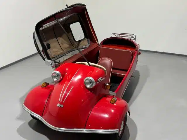 Roter Messerschmitt Kabinenroller Cabriolet mit geöffnetem Verdeck, fotografiert in einer neutralen Umgebung.