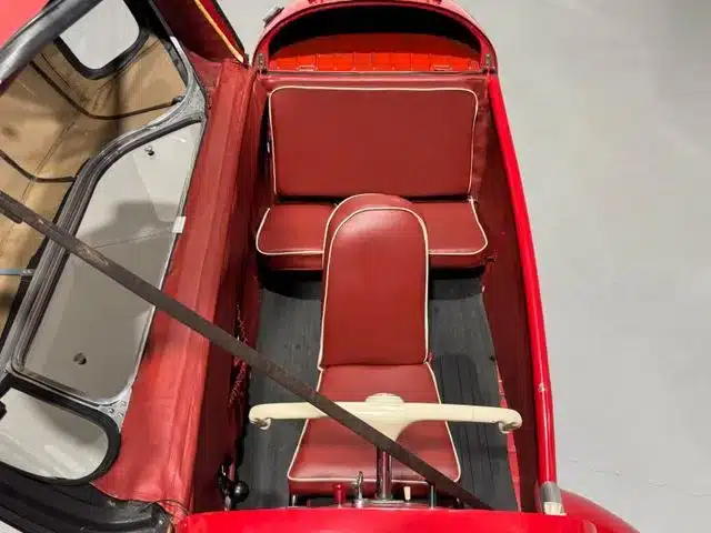 Innenraum eines offenen Messerschmitt Kabinenroller Cabriolet von oben fotografiert, mit zwei roten Sitzen und minimalistischem Lenkrad.