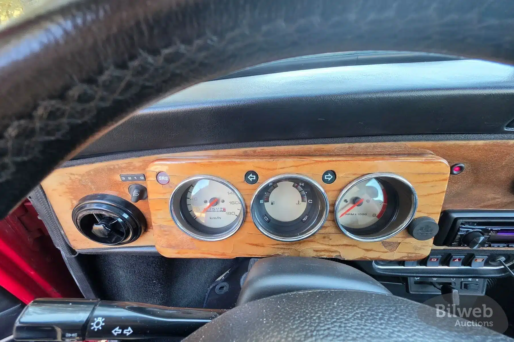 Armaturenbrett und Tachoeinheit eines Rover Mini Cooper 1997 mit Holzverkleidung und klassischen Rundinstrumenten.