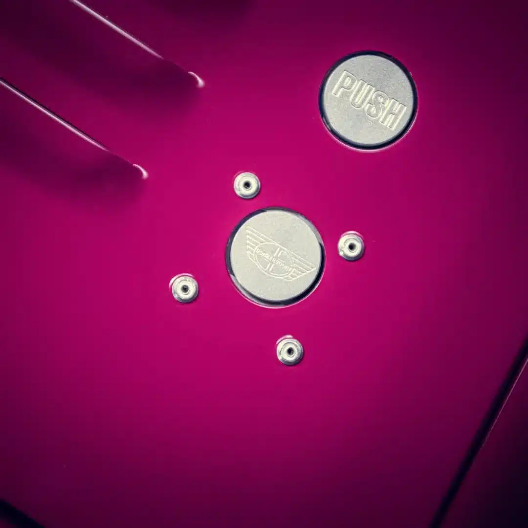 Nahaufnahme eines Tankdeckels mit Donkervoort-Logo und Push-Schriftzug auf pinkem Fahrzeuglack.