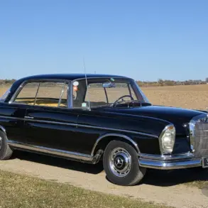 Schwarzes Mercedes-Benz 300 SE Coupé der Baureihe W112, Baujahr 1964, auf einem Feldweg vor offenem Landschaftshintergrund