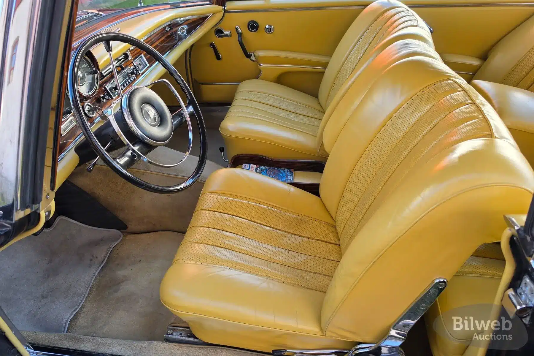 Edler Innenraum mit gelben Ledersitzen und Holzarmaturen eines Mercedes-Benz 300 SE Coupé (W112) von 1964.