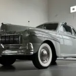Grauer Mercury Eight V8 Oldtimer mit breitem Chromgrill in einer modernen Halle