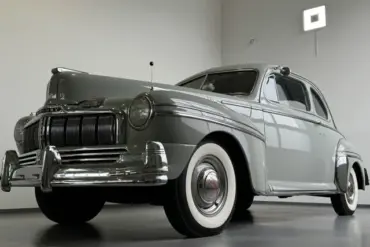 Grauer Mercury Eight V8 Oldtimer mit breitem Chromgrill in einer modernen Halle