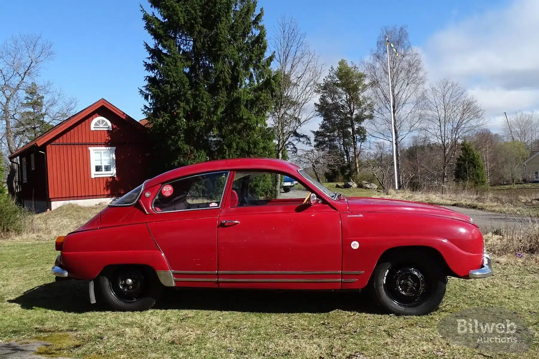 Roter Saab 96 Monte Carlo 850 2-Takt von 1966 mit Patina und Originallack, Seitenansicht, auf Wiese vor Haus