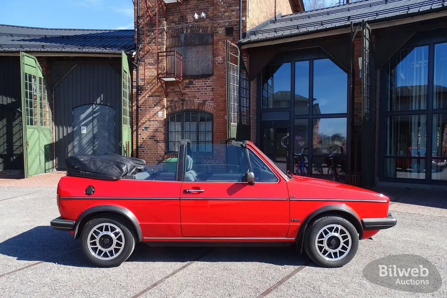 Originales VW Golf Cabriolet 1.8 GLI Baujahr 1985 in Marsrot mit geöffnetem Stoffverdeck und Snowflake-Leichtmetallfelgen