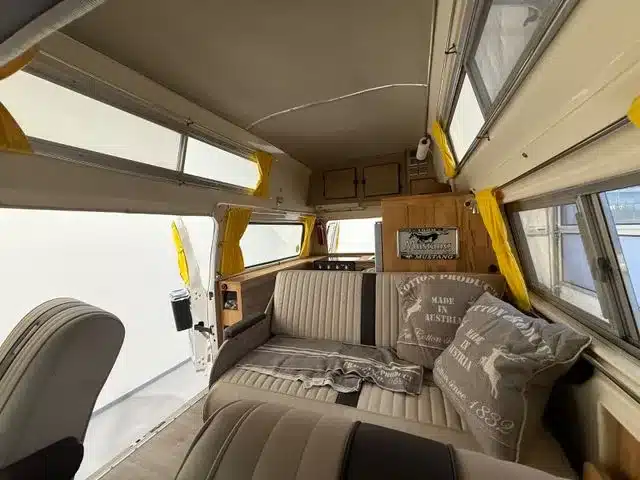 Blick in den Innenraum eines Ford Econoline Custom-Minihome-Campervans der 1970er Jahre mit Sitzbank, Fenstern und Stauraum.