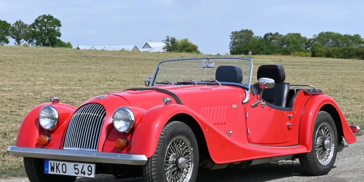 Roter Morgan 4/4 Roadster von 1998 mit Speichenrädern und schwarzem Interieur, fotografiert auf einer Landstraße.