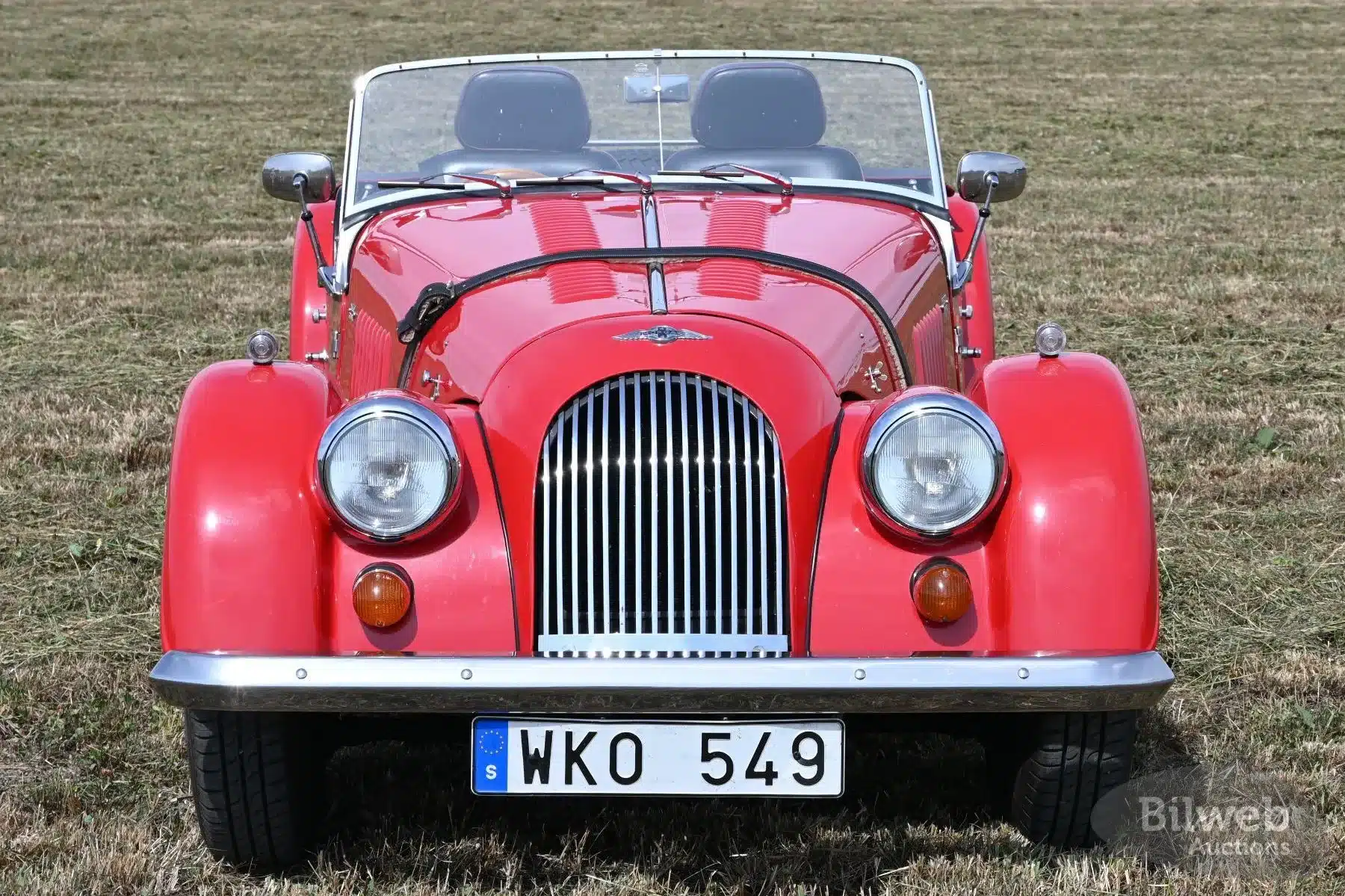 Frontansicht eines roten Morgan 4/4 Roadster von 1998 auf einer Wiese, Nummernschild WKO 549, Bilweb Auctions.