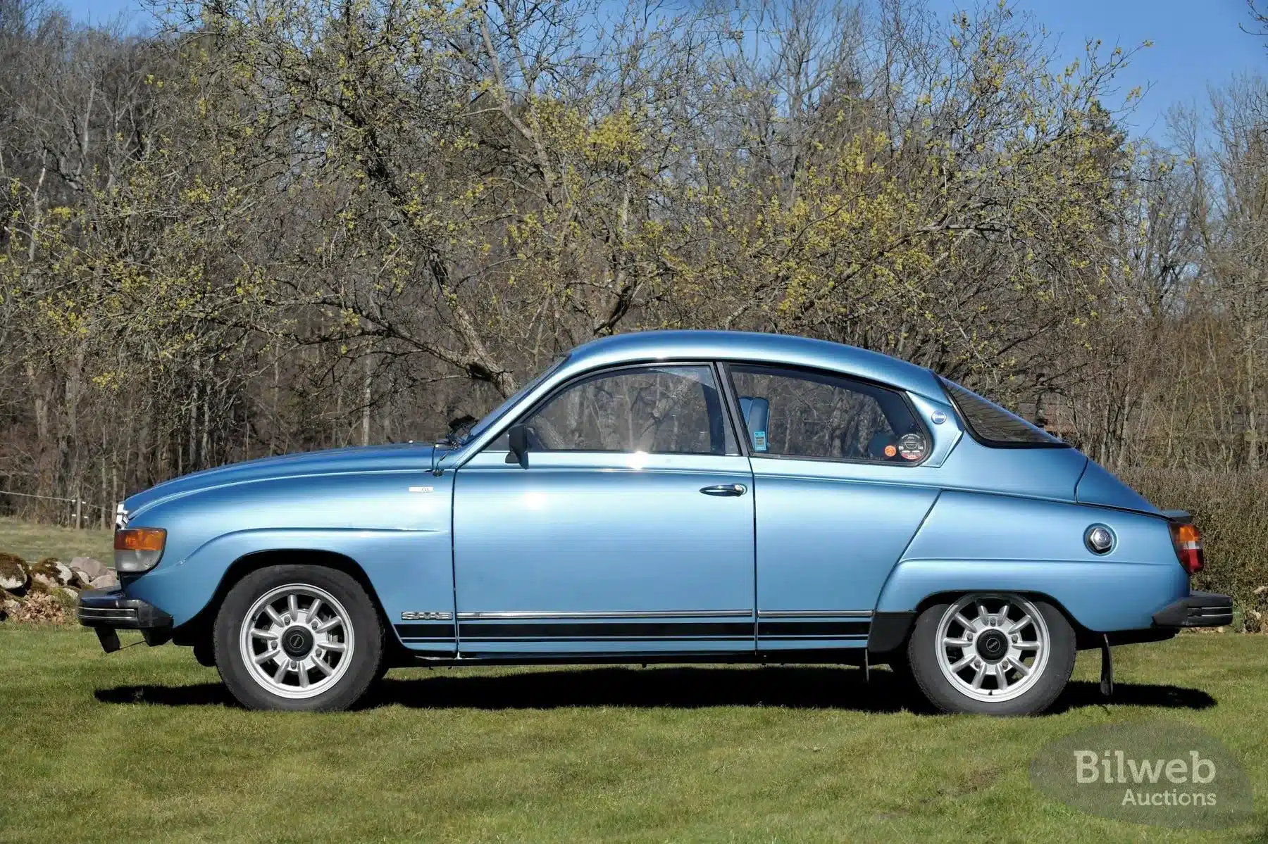 Saab 96 Jubileum V4 von 1980 in Aquamarin Metallic, Seitenansicht, auf einer Wiese stehend