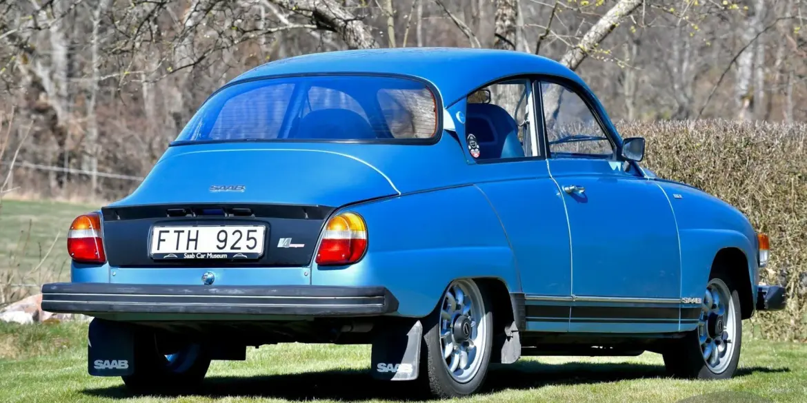 Saab 96 Jubileum V4 Baujahr 1980 in Aquamarine Blue Metallic mit Ronal-Felgen, Heckansicht auf einer Wiese