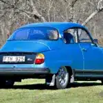 Saab 96 Jubileum V4 Baujahr 1980 in Aquamarine Blue Metallic mit Ronal-Felgen, Heckansicht auf einer Wiese