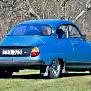 Saab 96 Jubileum V4 Baujahr 1980 in Aquamarine Blue Metallic mit Ronal-Felgen, Heckansicht auf einer Wiese