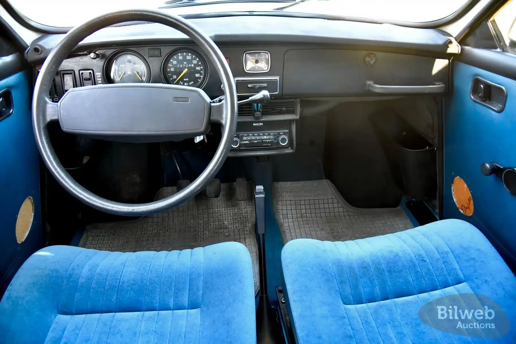 Innenraum eines Saab 96 Jubileum V4 von 1980 mit blauen Sitzen und klassischen Armaturen.