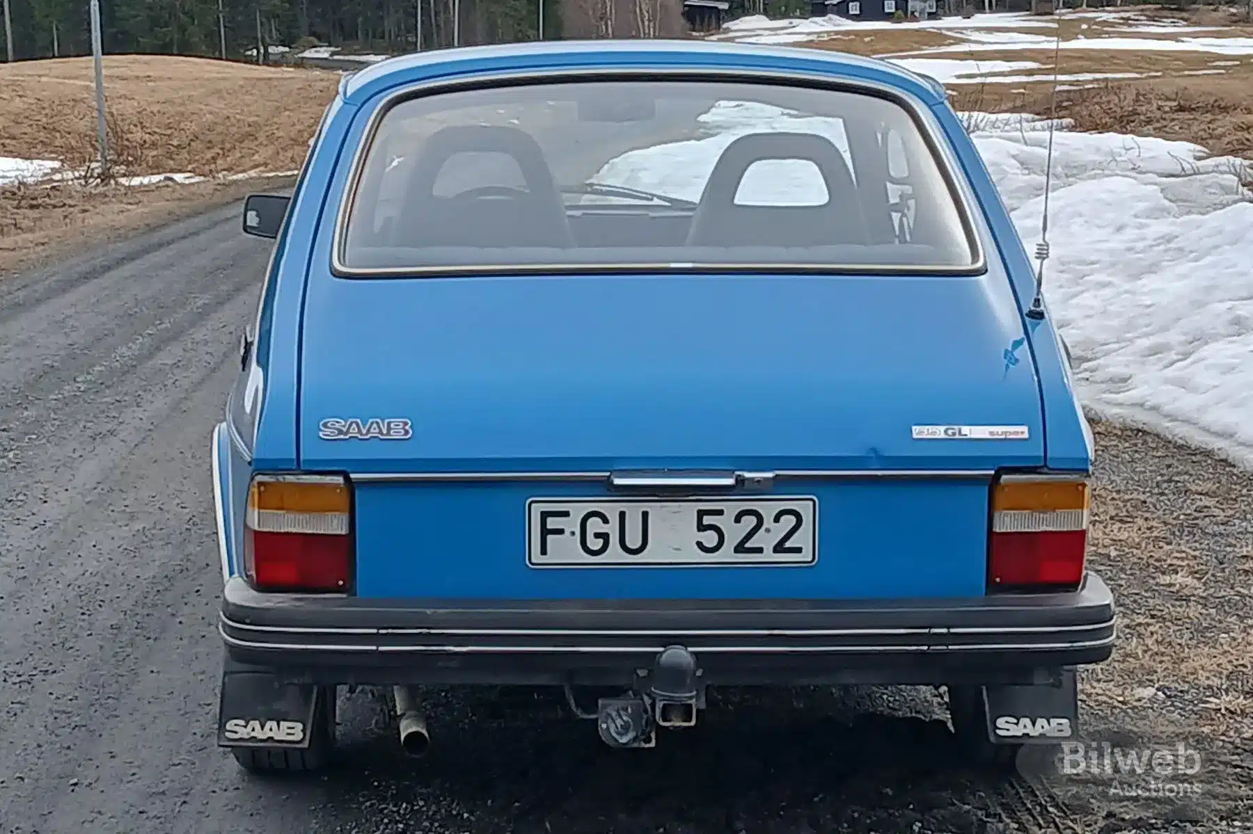 Blaue Saab 99 GL Limousine von 1977, fotografiert von hinten auf einer Landstraße.