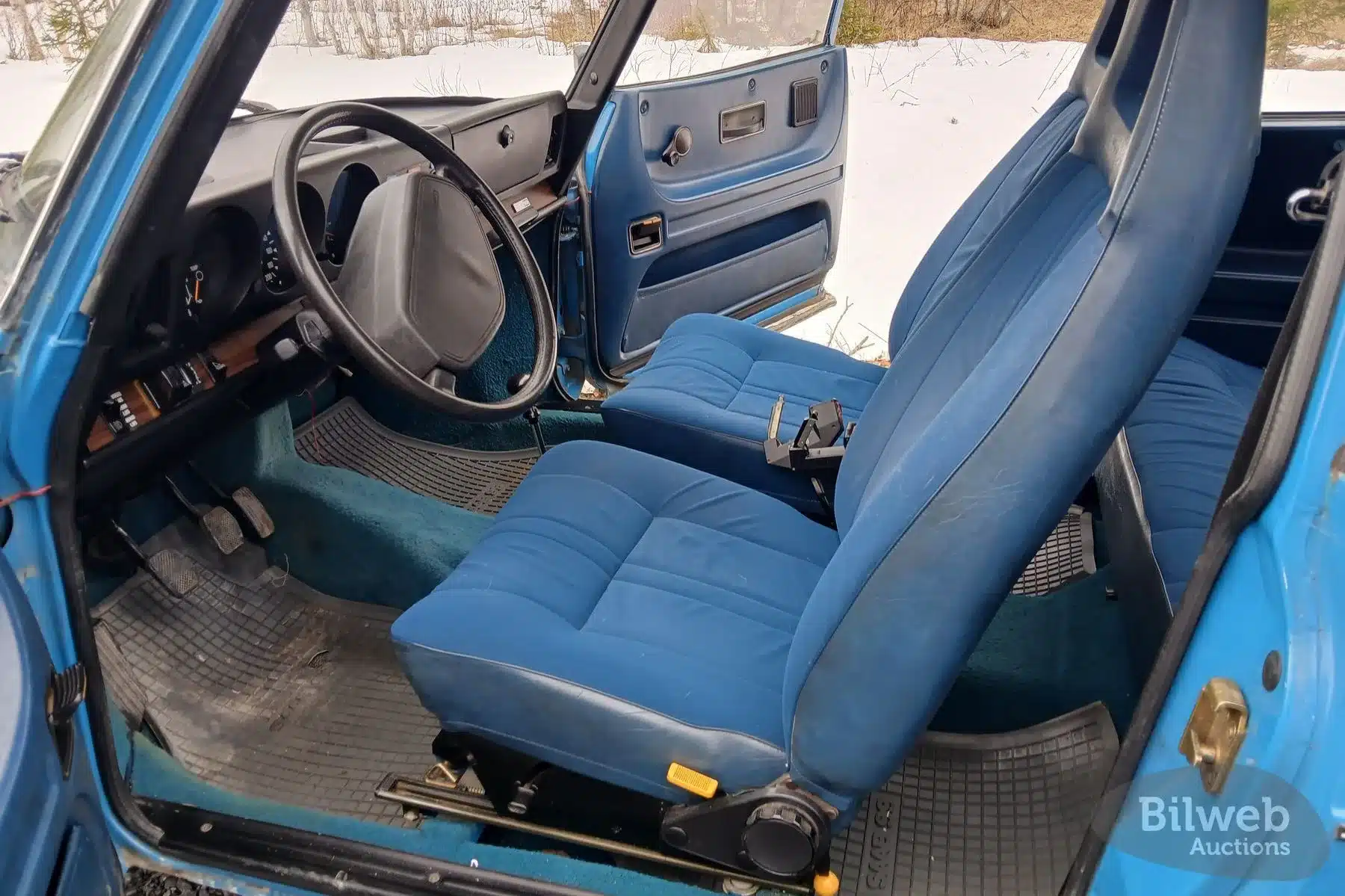 Blick in den Innenraum eines Saab 99 GL 2,0 von 1977 mit blauen Sitzen und Armaturenbrett.