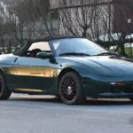 Lotus Elan 1.6 Turbo 16V aus dem Jahr 1991 in Dunkelgrün mit geschlossenem Verdeck und schwarzen Alufelgen, fotografiert im Freien.