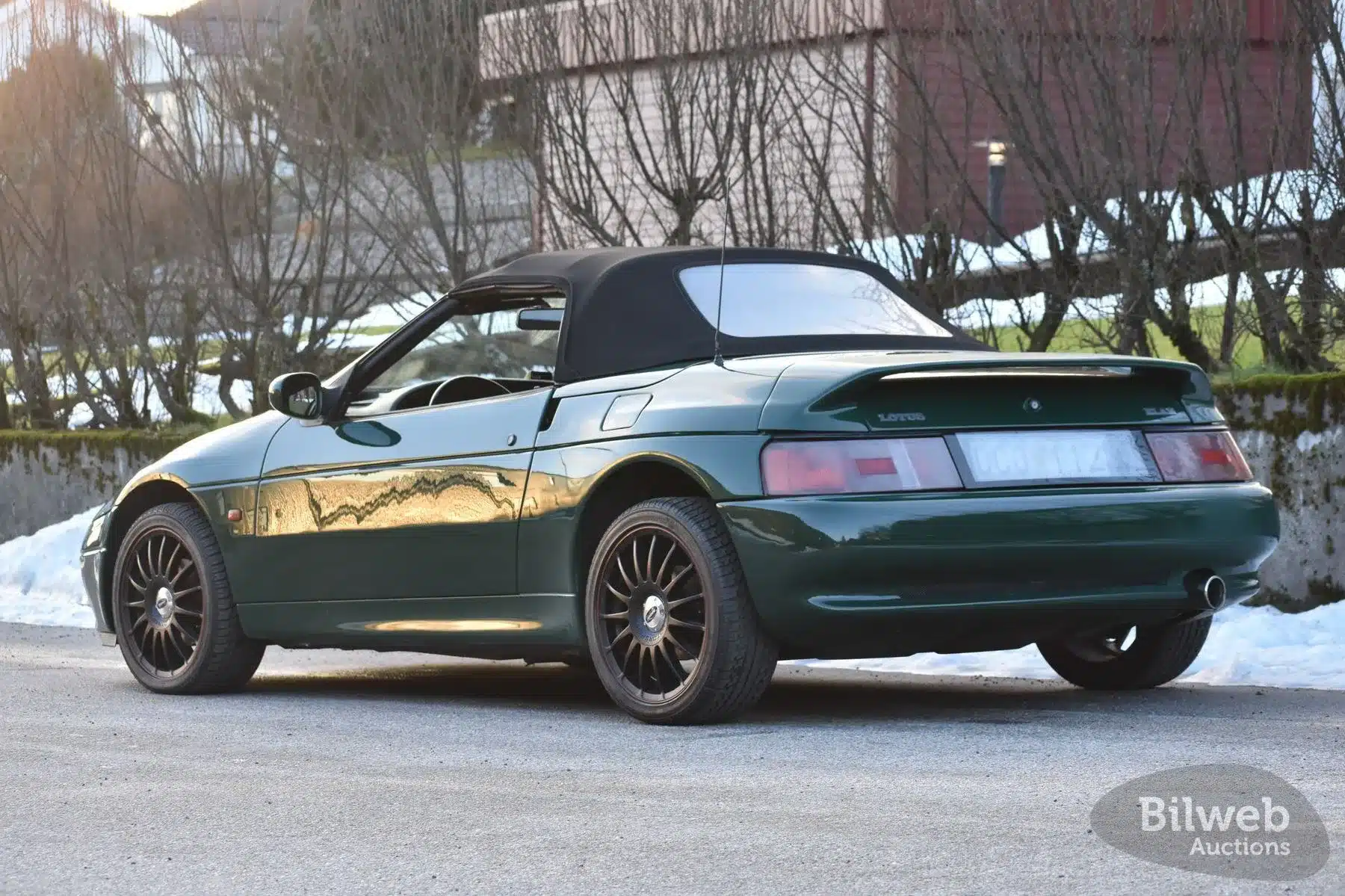 Dunkelgrüner Lotus Elan M100 Turbo Cabriolet von 1991, seitliche Heckansicht mit geschlossenem Verdeck.
