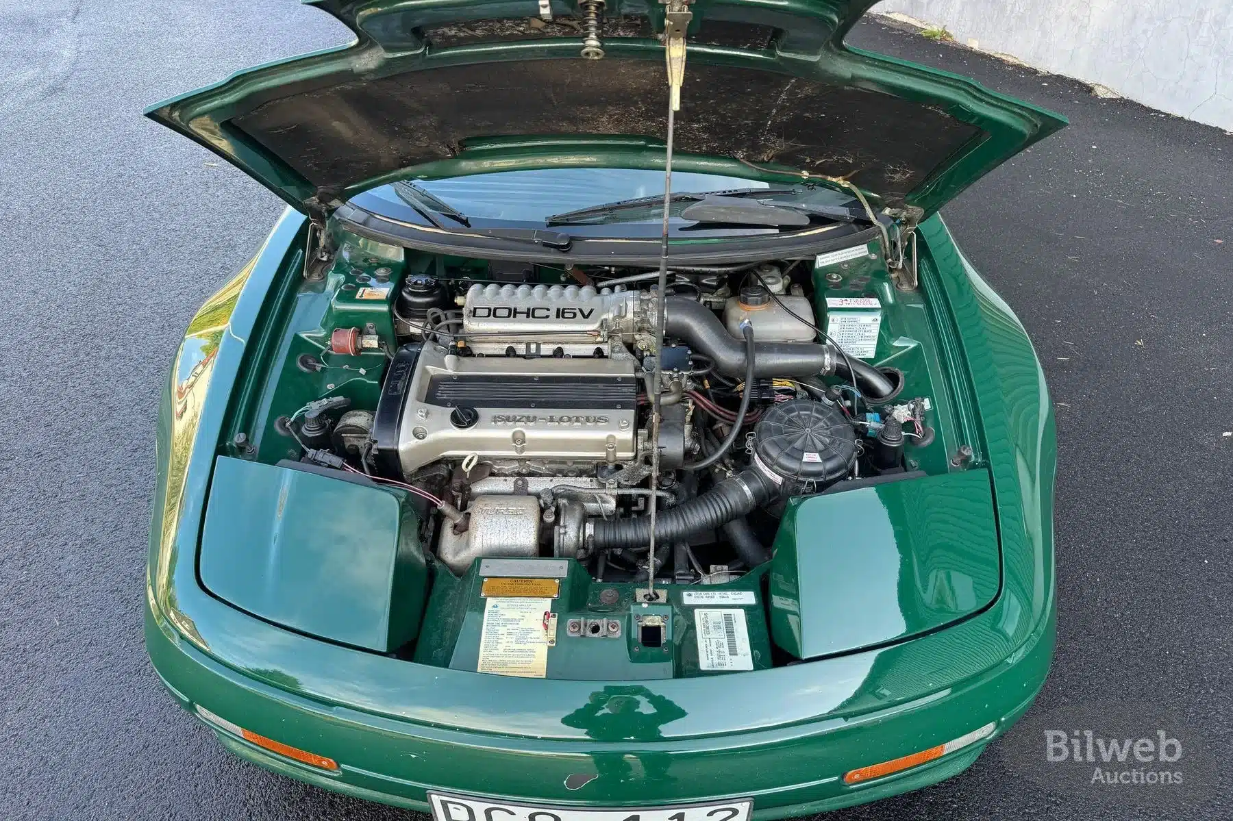 Geöffneter Motorraum eines Lotus Elan M100 Turbo 16V von 1991, dunkelgrüne Karosserie, Sicht auf Isuzu-Lotus-Turbomotor.