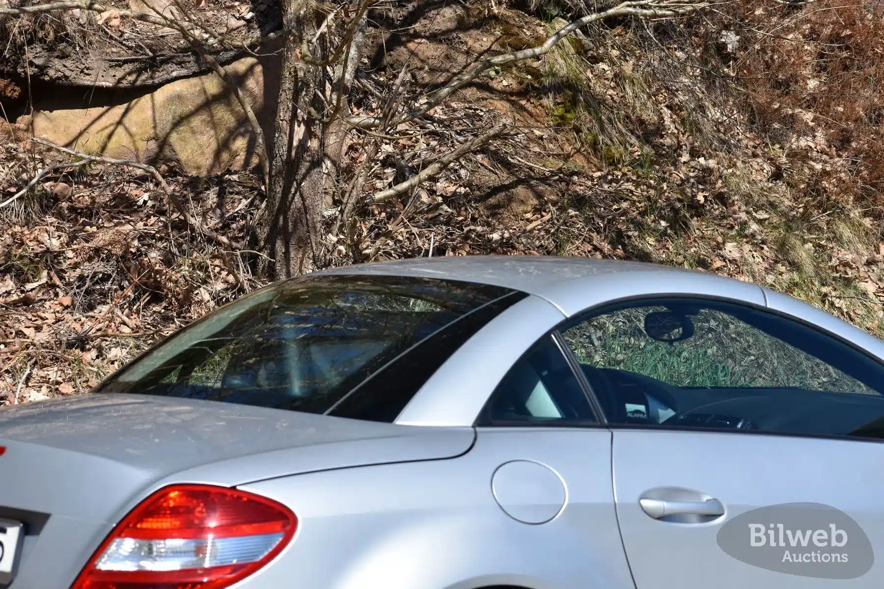 Silberner Mercedes-Benz SLK 280 R171 mit geschlossenem Dach, Seitenansicht des Hecks und Cockpits im Freien