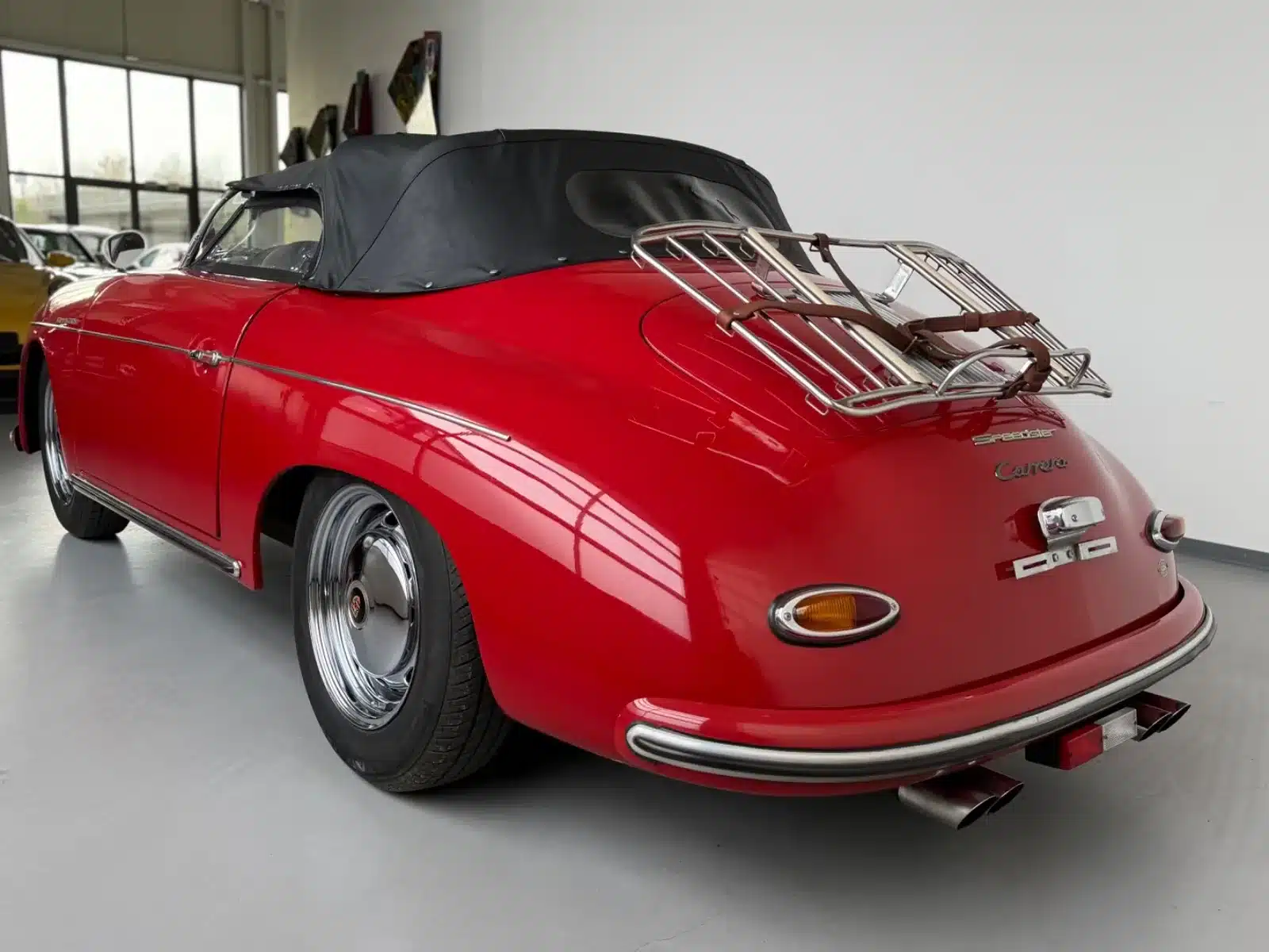 Heckansicht eines roten Porsche 356 Speedster Replica von 1992 mit geschlossenem Verdeck und Gepäckträger.