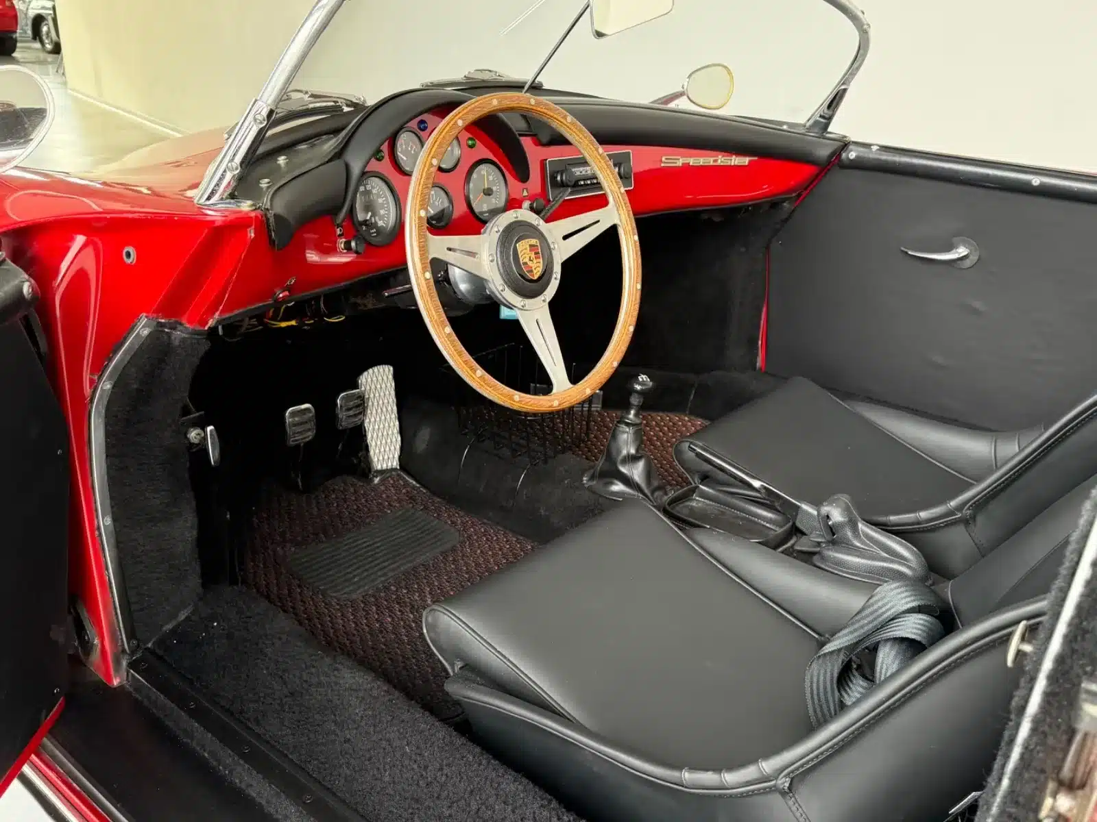 Innenraum eines roten Porsche 356 Speedster Replica mit Holzlenkrad und schwarzer Lederausstattung