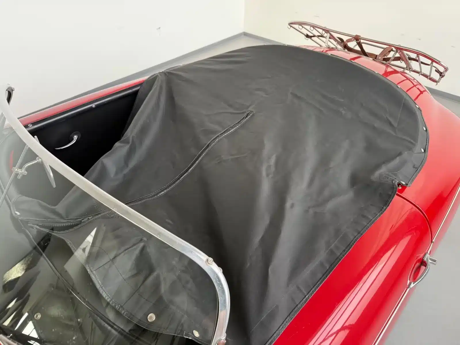 Cockpit eines roten Porsche 356 Speedster Replica, abgedeckt mit einer schwarzen Persenning.