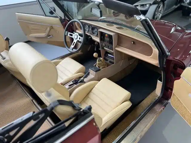 Cockpit und Innenraum eines späten Fiat 124 Spider Cabriolets mit beiger Leder-Innenausstattung und klassischen Rundinstrumenten.