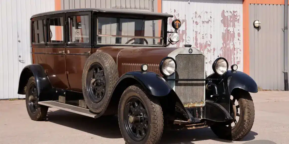 Seitenansicht eines unrestaurierten Mercedes-Benz 320 Mannheim 12/55 PS W04 Baujahr 1928 mit brauner und schwarzer Lackierung, abgenutztem Ersatzrad und matter Oberfläche.