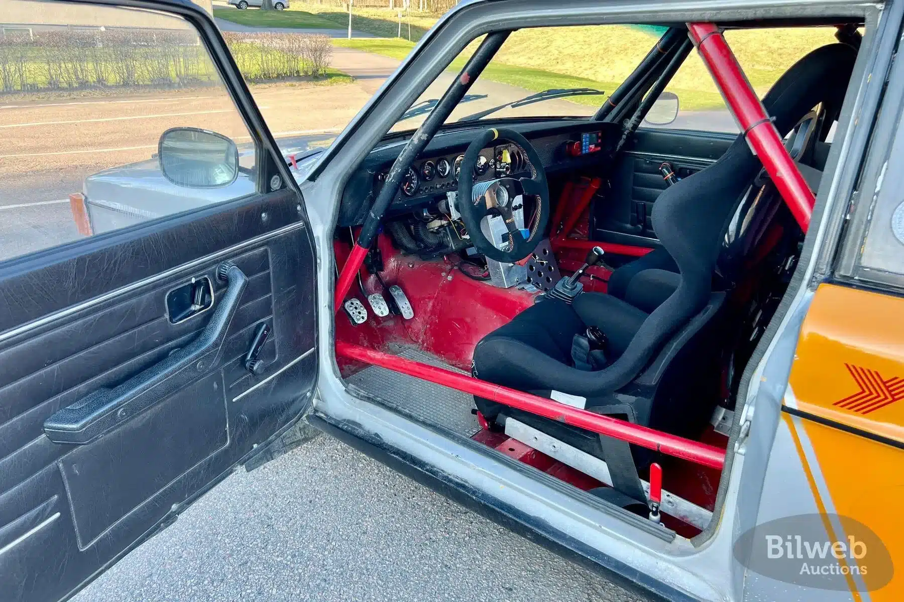 Innenaufnahme eines historischen Volvo 142 Rallyeautos mit Überrollkäfig, Sportsitz und Motorsportausstattung.