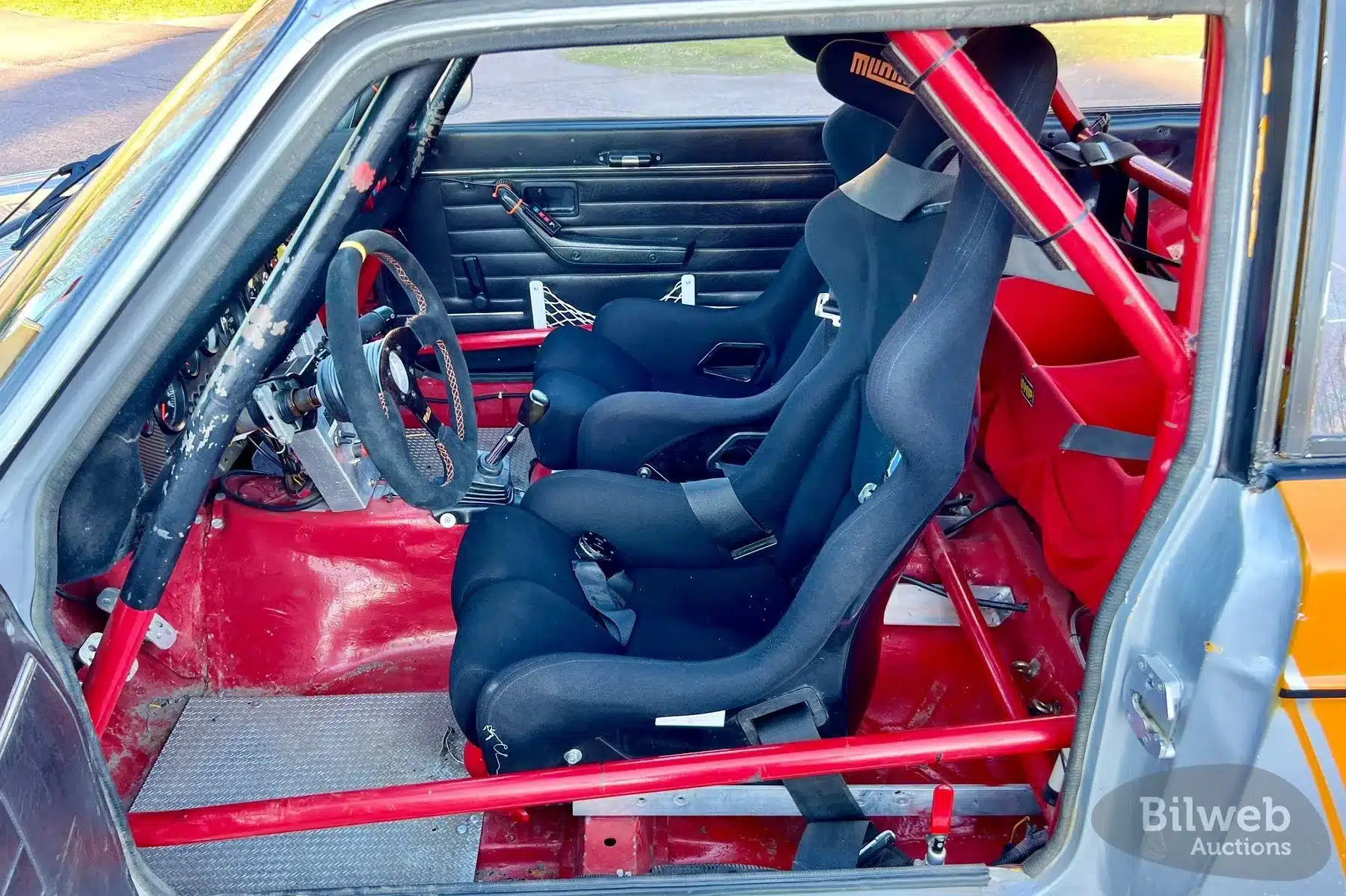 Innenraum eines Volvo 142 Rallyeautos mit Sicherheitskäfig, Sportsitzen und spartanischer Ausstattung.