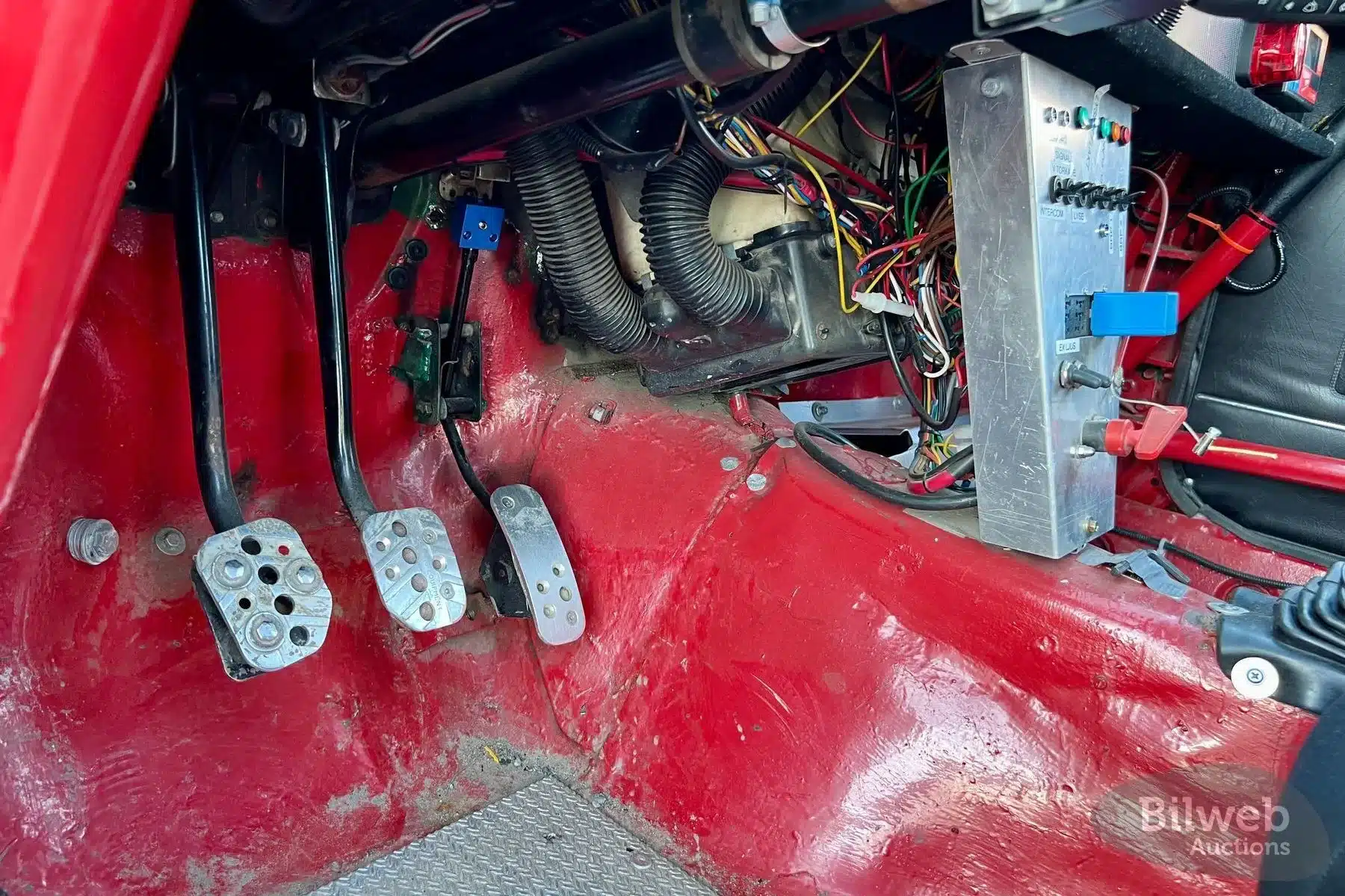 Pedale und Elektrik eines Volvo 142 als historisches Rallyefahrzeug, spartanischer Innenraum mit sichtbarer Verkabelung und Motorsport-Komponenten.