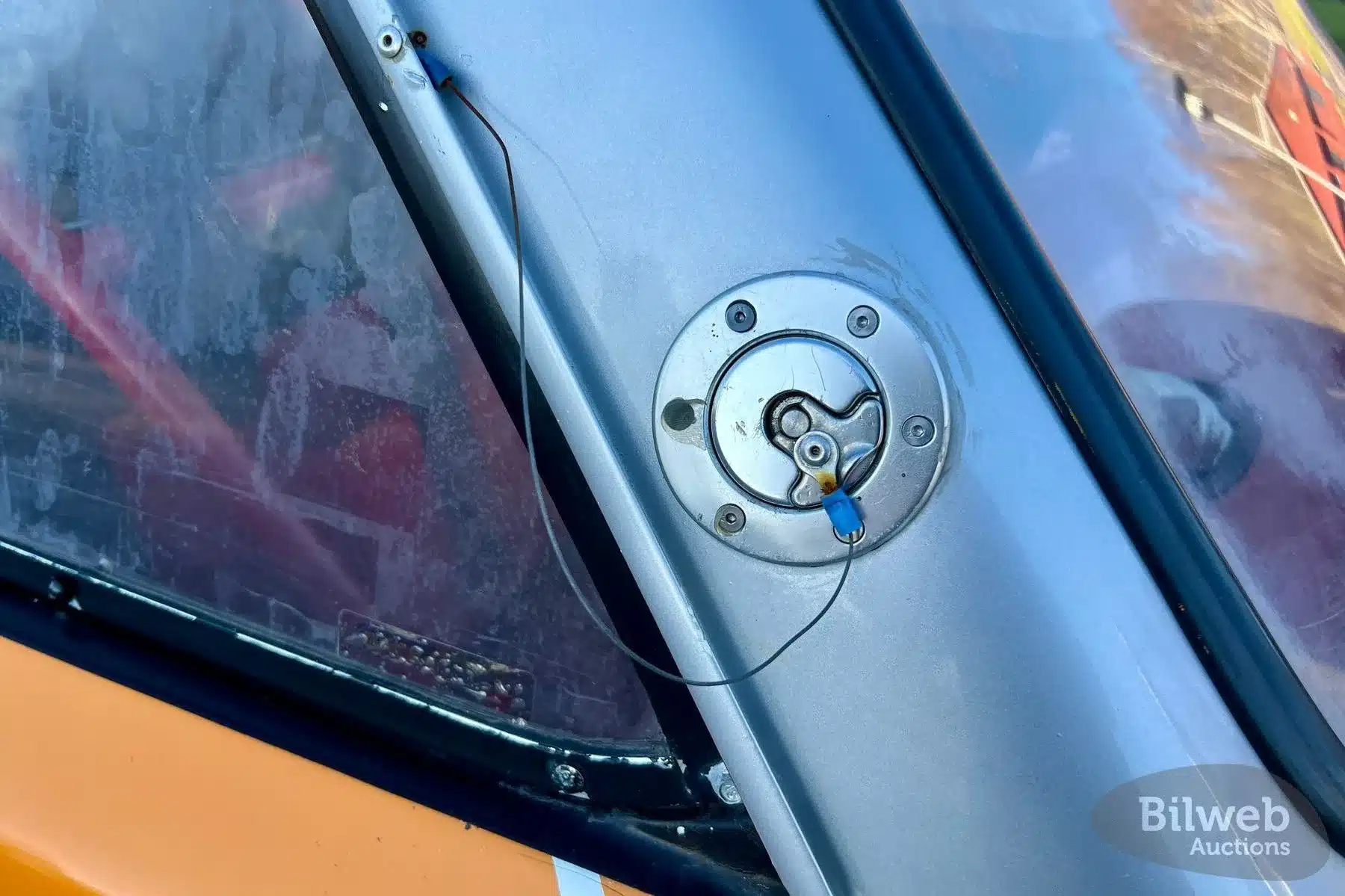 Detailbild des Tankdeckels und des Seitendreiecksfensters am Volvo 142 Rallyefahrzeug mit Spuren intensiver Nutzung.