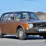 Brauner Volvo 144 GL B20 von 1973 geparkt vor Küstenkulisse